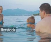 Young parents and little son bathing in the sea. Mom and child playing with windup frog. Family summer vacationnLicense this clip: https://fillerstock.com/video/10465