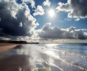 Prompt Midjourney : Sunlight streaming through fluffy clouds onto a tranquil beach --ar 3:2 --v 6.0